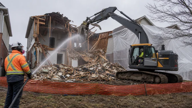 Excavator operator and ground worker completing a house demolition